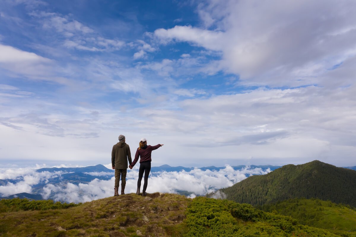 man and woman standing on top of mountain